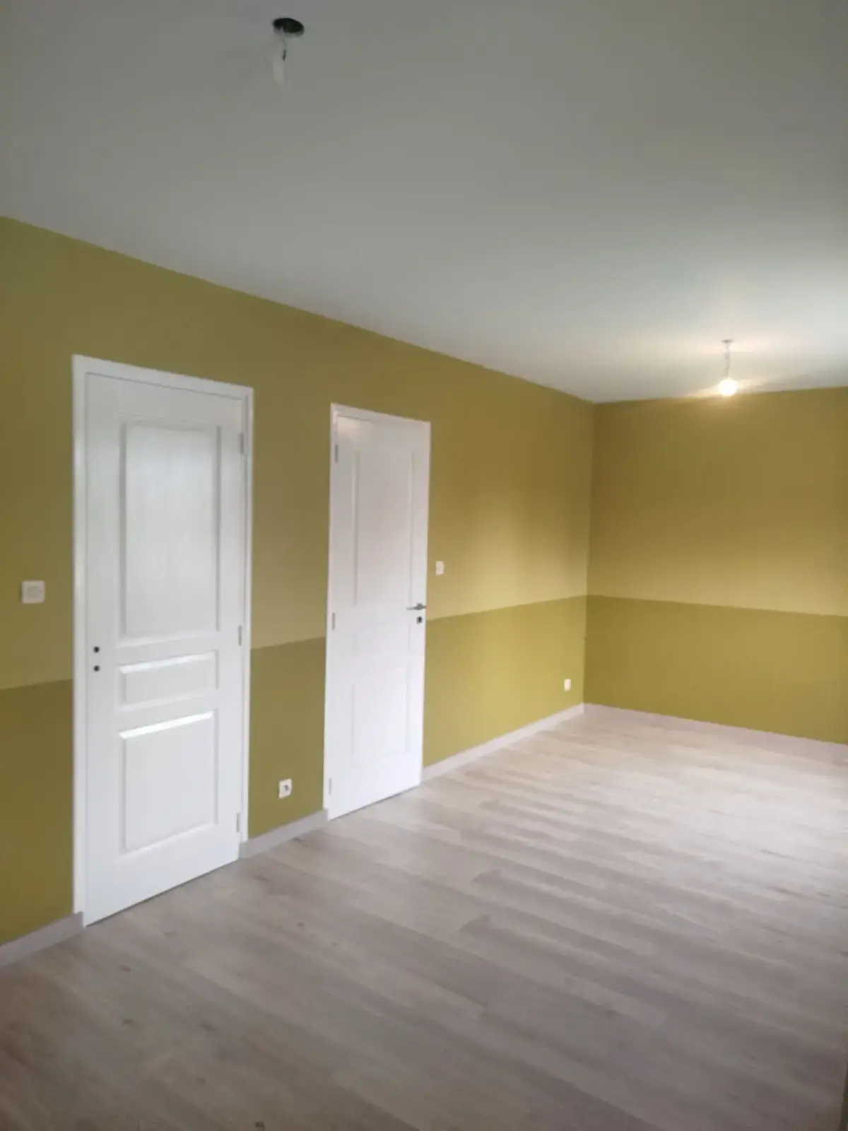 Séjour avec soubassement doré, murs crème et sol imitation parquet
