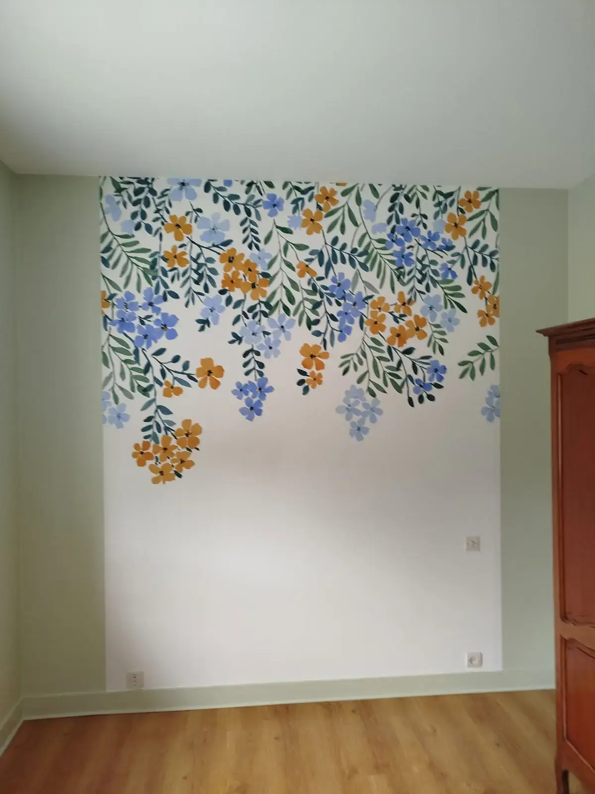 Papier peint à grandes fleurs bleues et orange sur un mur blanc